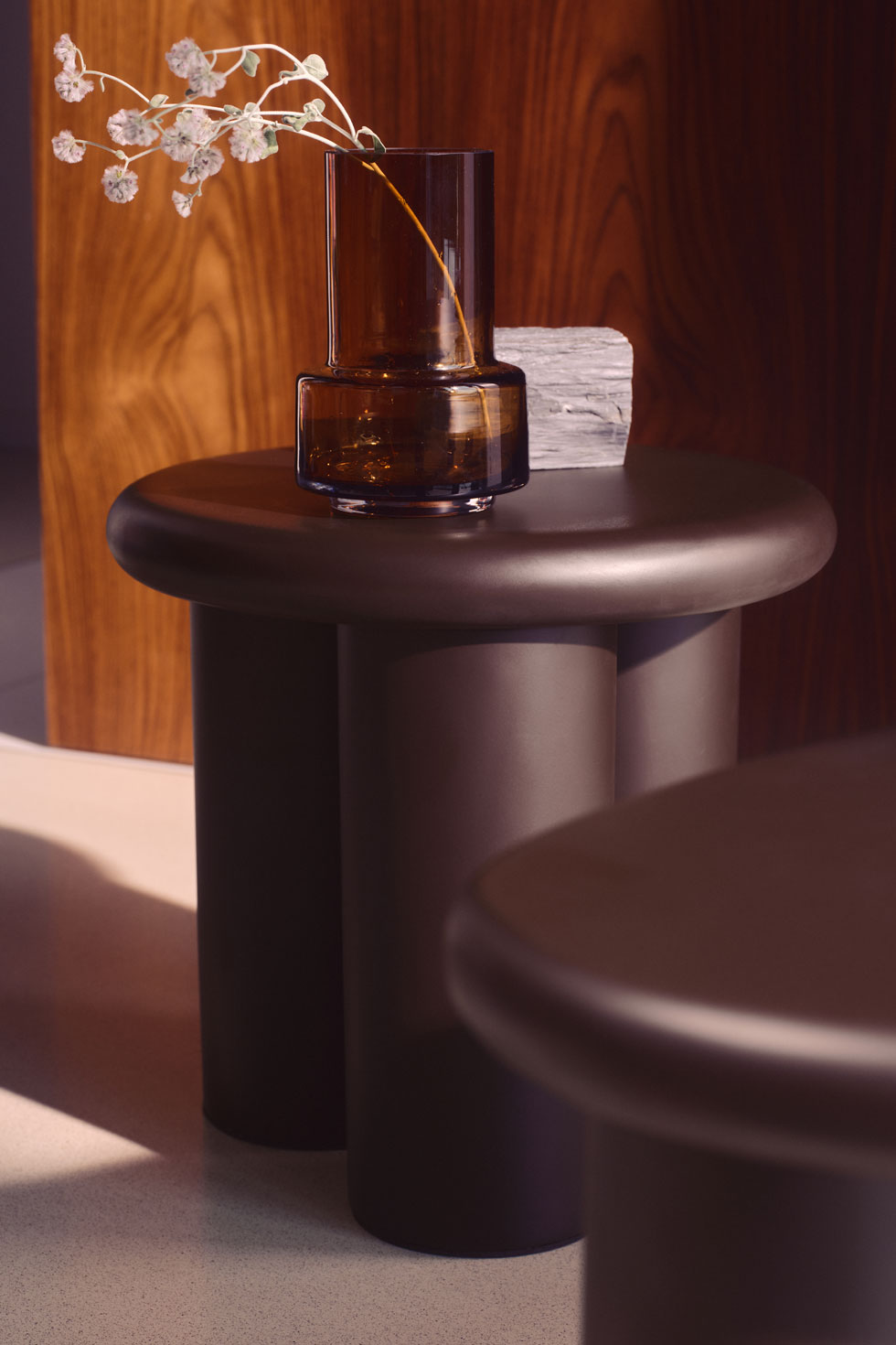 Amber glass vase on a sculptural dark side table from H&M HOME.