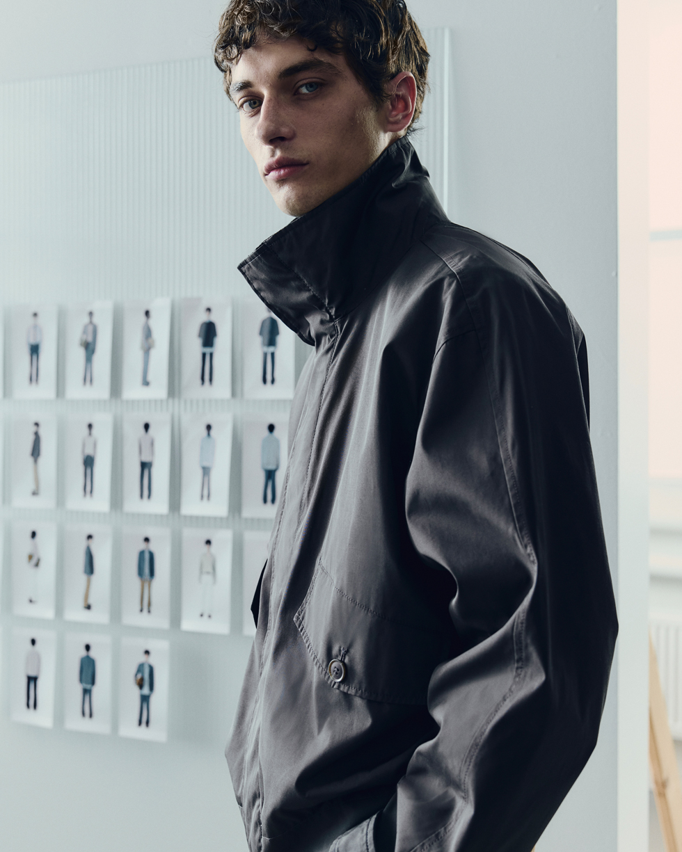 Model wearing a dark gray high-collar jacket from A/W ATELIER 2025